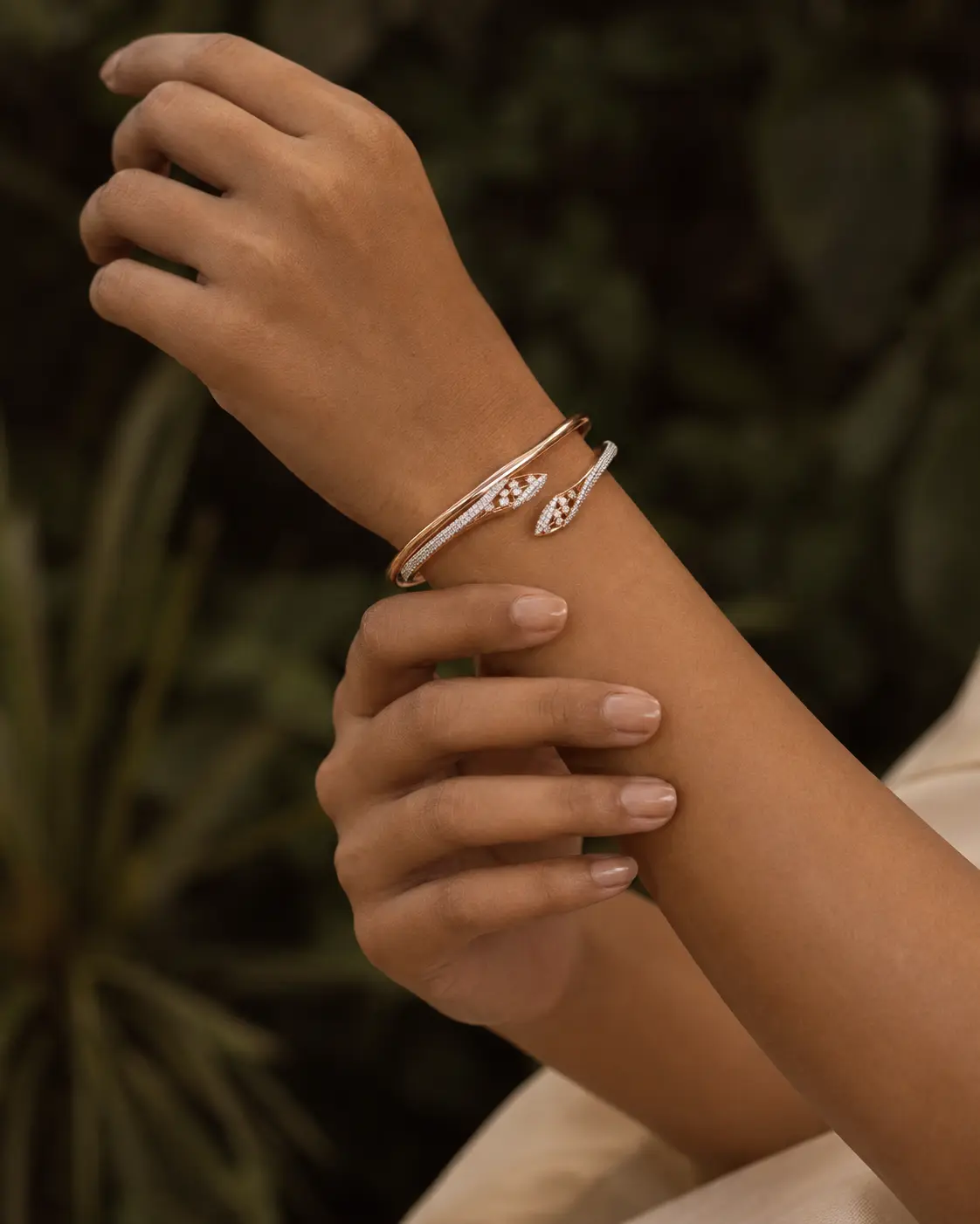 Rose gold serpent bracelet photographed against a deep botanical setting